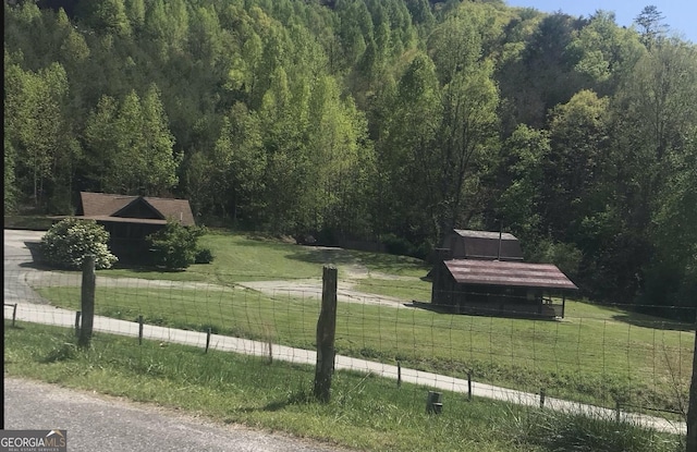 view of community featuring a view of trees, a view of rural / pastoral area, and an outbuilding