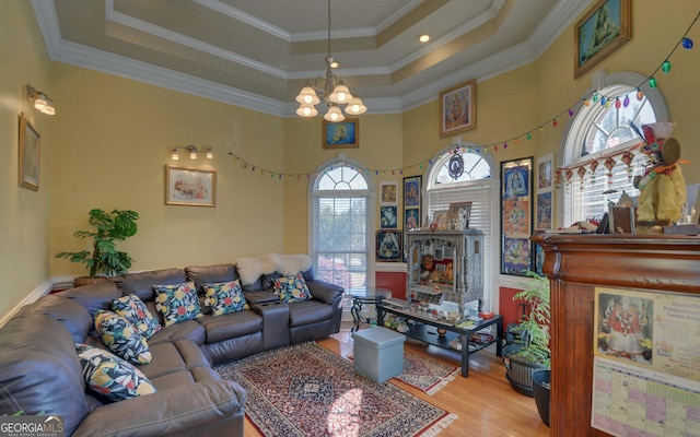 living area featuring wood finished floors, a chandelier, a tray ceiling, ornamental molding, and a high ceiling