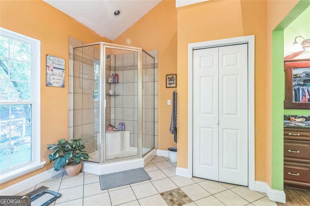 bathroom with a closet, healthy amount of natural light, a stall shower, and lofted ceiling