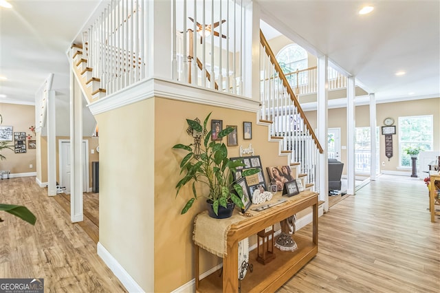 stairway with wood finished floors, baseboards, ornamental molding, and recessed lighting