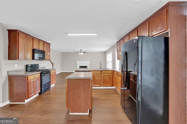 1280 Chandler Ridge Dr, Lawrenceville, GA 30045 - kitchen with black appliances, dark wood-style flooring, a kitchen island, a peninsula, and a fireplace