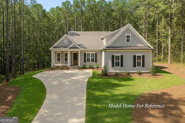 view of front of home with a view of trees, a front lawn, and covered porch