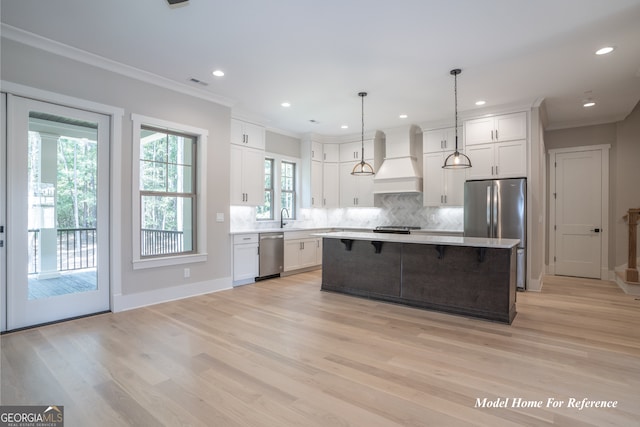 kitchen featuring custom exhaust hood, appliances with stainless steel finishes, tasteful backsplash, light countertops, and crown molding