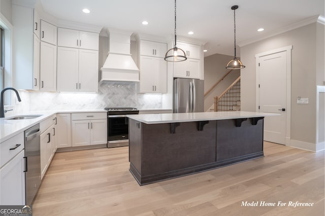 kitchen featuring appliances with stainless steel finishes, a sink, premium range hood, a center island, and tasteful backsplash