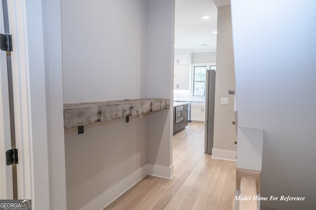 hall featuring light wood-type flooring, recessed lighting, and baseboards