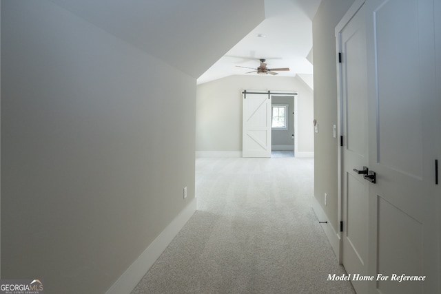 corridor with a barn door, vaulted ceiling, light carpet, and baseboards