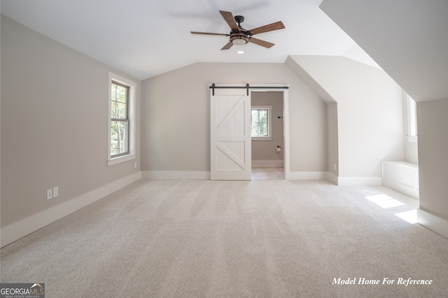 bonus room featuring vaulted ceiling, a barn door, a ceiling fan, plenty of natural light, and carpet flooring