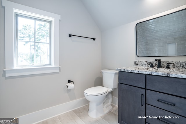 bathroom with baseboards, vaulted ceiling, toilet, and vanity