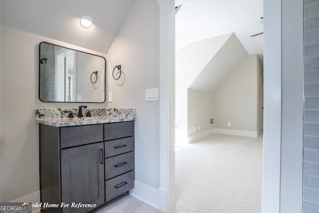 bathroom featuring lofted ceiling, vanity, and baseboards