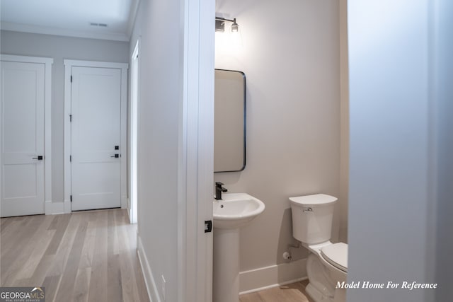 bathroom featuring wood finished floors, baseboards, toilet, and ornamental molding