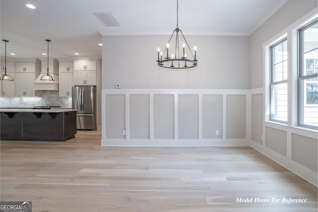 unfurnished dining area with a chandelier, ornamental molding, light wood-style floors, recessed lighting, and a decorative wall