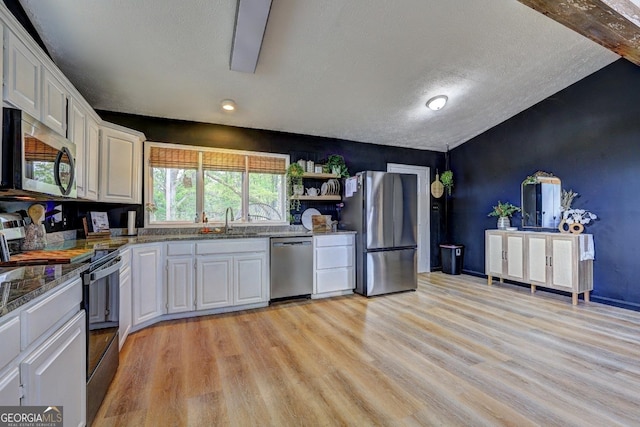 124 Laurel Dr, Barnesville, GA 30204 - kitchen with appliances with stainless steel finishes, a sink, white cabinets, light wood-type flooring, and dark stone counters