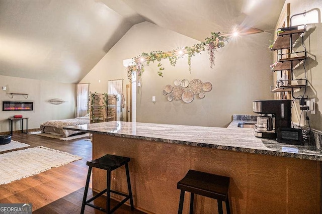 128 Graybrook Ct, Grayson, GA 30017 - kitchen with dark wood-type flooring, a peninsula, open floor plan, vaulted ceiling, and dark stone counters