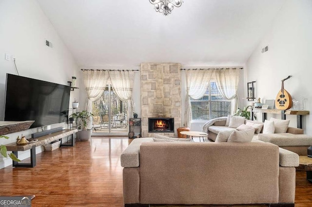128 Graybrook Ct, Grayson, GA 30017 - living room featuring a stone fireplace, wood finished floors, plenty of natural light, high vaulted ceiling, and a chandelier