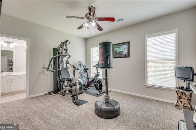 exercise room featuring a ceiling fan, healthy amount of natural light, and light colored carpet