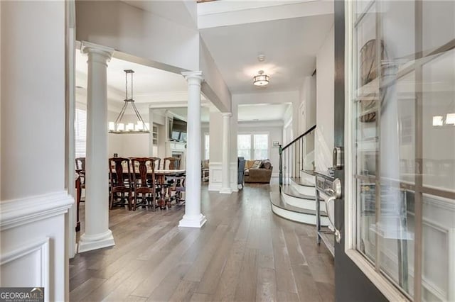 entrance foyer featuring ornate columns, wood-type flooring, and stairway