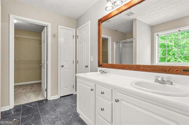 182 Garden Manor Ct, Loganville, GA 30052 - full bath with a textured ceiling, a shower stall, double vanity, marble finish flooring, and a spacious closet