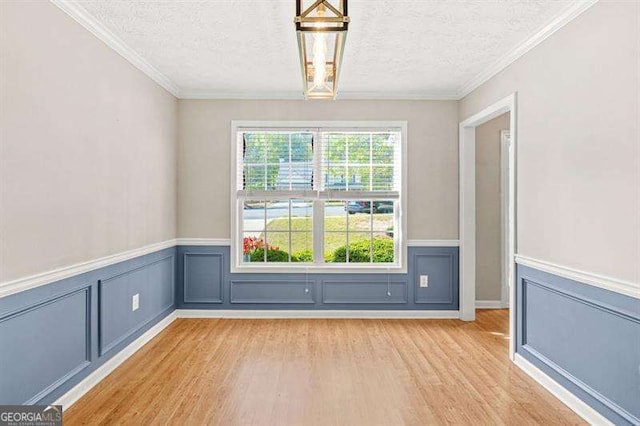 182 Garden Manor Ct, Loganville, GA 30052 - empty room featuring light wood-type flooring, a textured ceiling, a wainscoted wall, and crown molding
