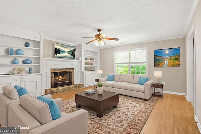 182 Garden Manor Ct, Loganville, GA 30052 - living area with a textured ceiling, a ceiling fan, light wood finished floors, crown molding, and a fireplace