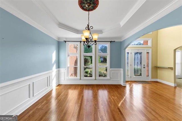 10890 Regal Frst, Suwanee, GA 30024 - unfurnished dining area with arched walkways, a chandelier, a raised ceiling, a decorative wall, and wood finished floors