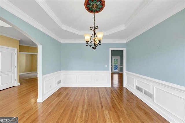 10890 Regal Frst, Suwanee, GA 30024 - unfurnished dining area with light wood finished floors, a raised ceiling, a chandelier, arched walkways, and wainscoting