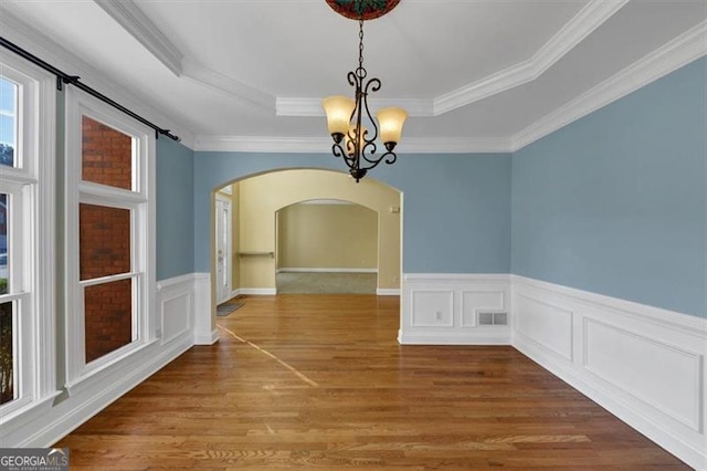 10890 Regal Frst, Suwanee, GA 30024 - unfurnished dining area with arched walkways, a chandelier, a tray ceiling, wood finished floors, and a wainscoted wall