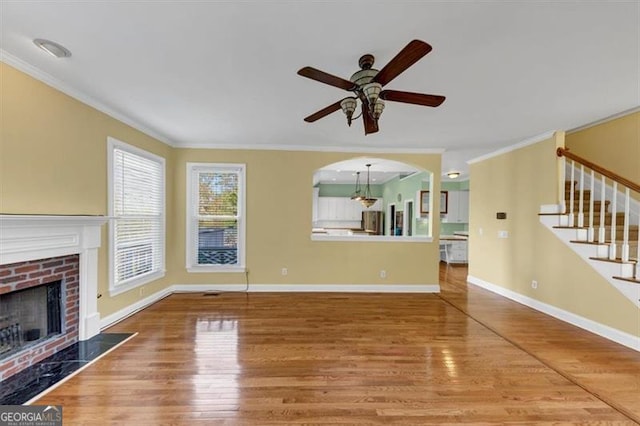 10890 Regal Frst, Suwanee, GA 30024 - unfurnished living room featuring ornamental molding, wood finished floors, a fireplace, a ceiling fan, and stairs