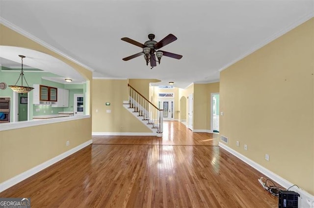 10890 Regal Frst, Suwanee, GA 30024 - unfurnished living room with stairway, arched walkways, wood finished floors, ceiling fan, and ornamental molding