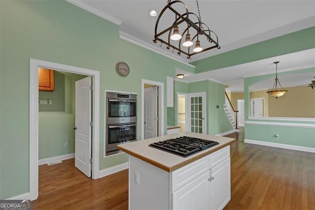 10890 Regal Frst, Suwanee, GA 30024 - kitchen featuring gas cooktop, stainless steel double oven, a chandelier, wood finished floors, and white cabinetry