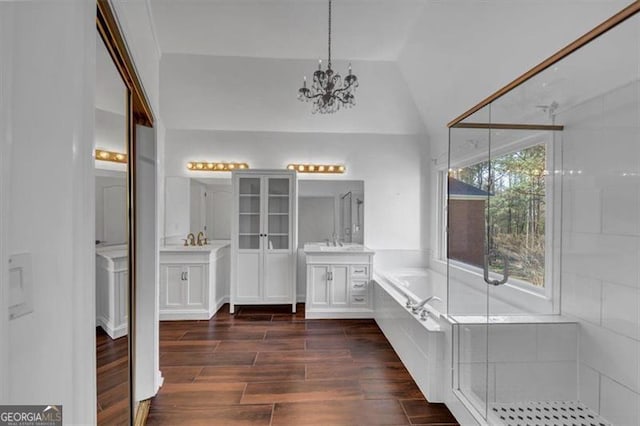 10890 Regal Frst, Suwanee, GA 30024 - bathroom featuring lofted ceiling, a garden tub, two vanities, a chandelier, and wood finished floors
