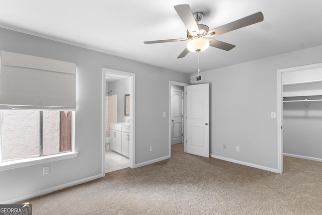 unfurnished bedroom featuring carpet flooring, a walk in closet, a closet, and baseboards