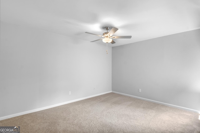 carpeted spare room featuring ceiling fan and baseboards