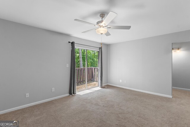 carpeted spare room featuring ceiling fan and baseboards