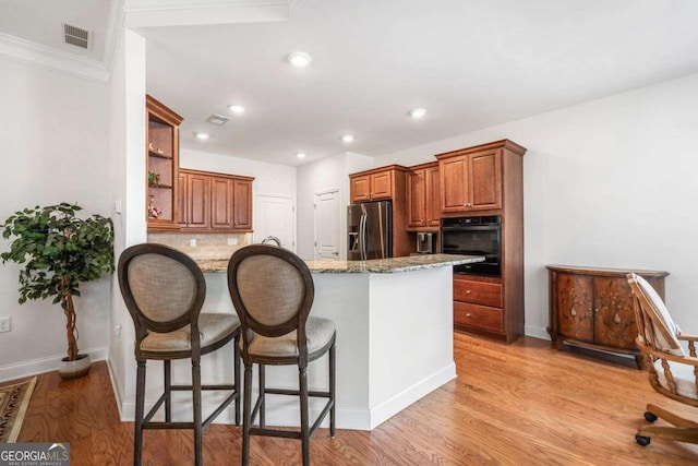 306 Cherokee Station Cir, Woodstock, GA 30188 - kitchen with stainless steel refrigerator with ice dispenser, black oven, a breakfast bar, backsplash, and a peninsula