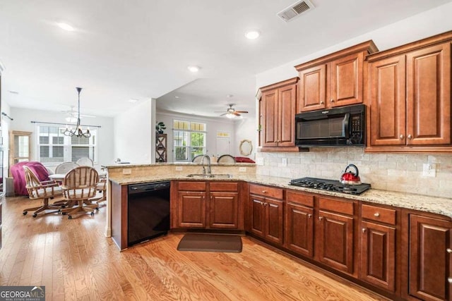 306 Cherokee Station Cir, Woodstock, GA 30188 - kitchen with black appliances, a peninsula, light wood finished floors, decorative backsplash, and light stone countertops