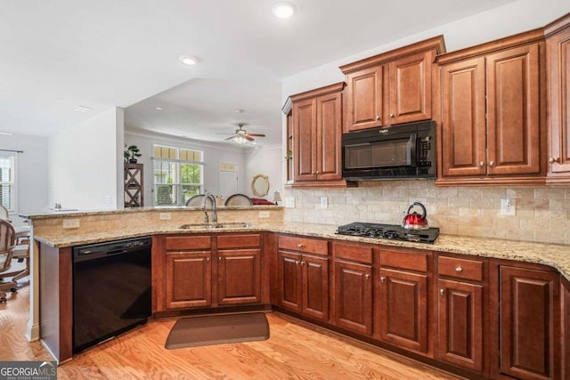 306 Cherokee Station Cir, Woodstock, GA 30188 - kitchen featuring black appliances, a peninsula, light wood-style floors, light stone countertops, and backsplash