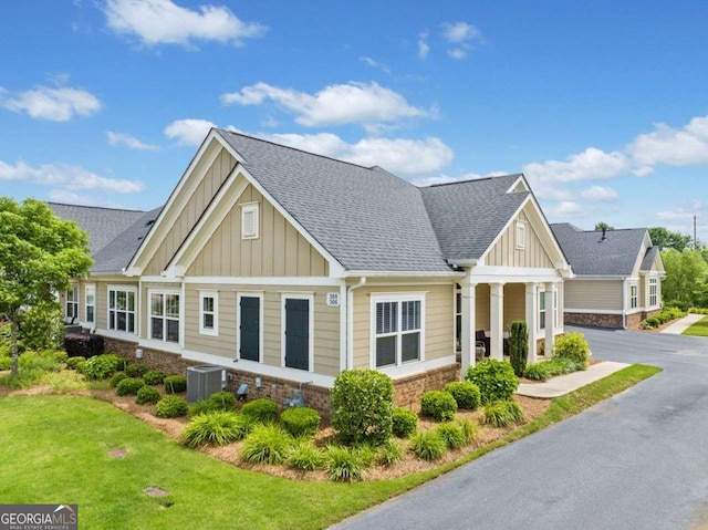306 Cherokee Station Cir, Woodstock, GA 30188 - view of front of house with board and batten siding, a shingled roof, a front yard, and stone siding