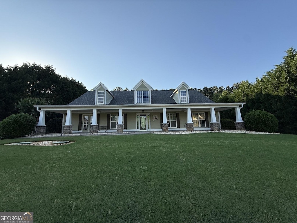 view of front of property featuring covered porch, a front yard, and stone siding