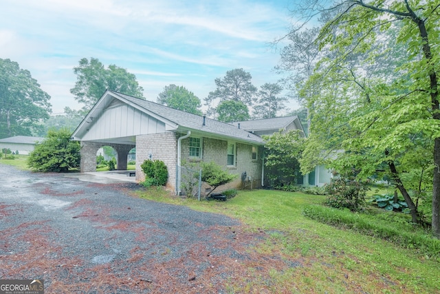 4244 Dorsey Ct SW, Lilburn, GA 30047 - view of side of home featuring brick siding, gravel driveway, a carport, and board and batten siding