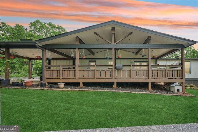 back of house at dusk featuring a lawn and a wooden deck