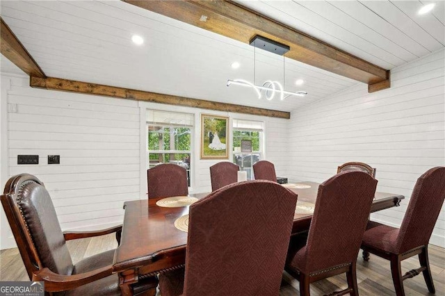 dining space with beamed ceiling, wooden walls, wood finished floors, a chandelier, and recessed lighting