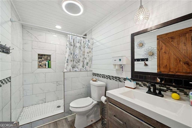 bathroom with a walk in shower, toilet, wood finished floors, vanity, and decorative backsplash
