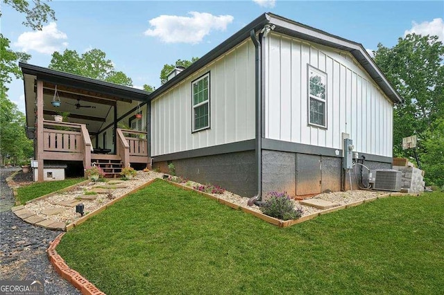 view of side of property with board and batten siding, a yard, and central AC