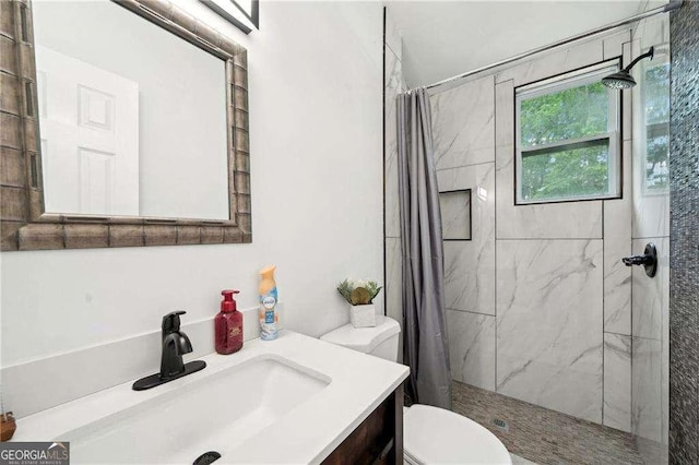 full bathroom featuring toilet, a tile shower, and vanity