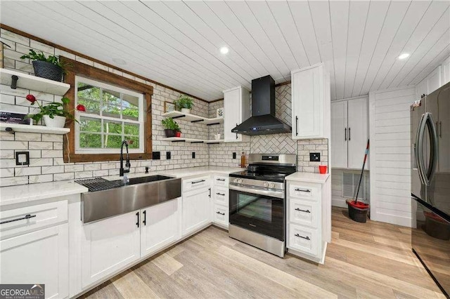 kitchen featuring stainless steel range with electric stovetop, open shelves, wall chimney range hood, a sink, and freestanding refrigerator