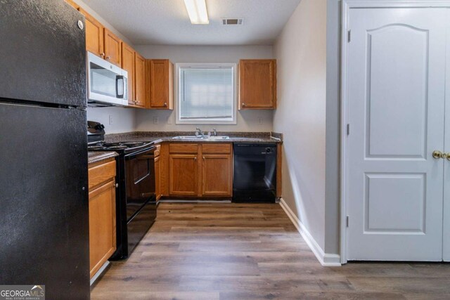 7623 Mcgillicuty Dr, Union City, GA 30291 - kitchen featuring black appliances, dark countertops, dark wood-style floors, a sink, and baseboards