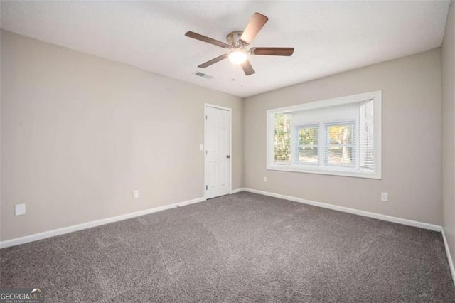 empty room with dark colored carpet, baseboards, and a ceiling fan