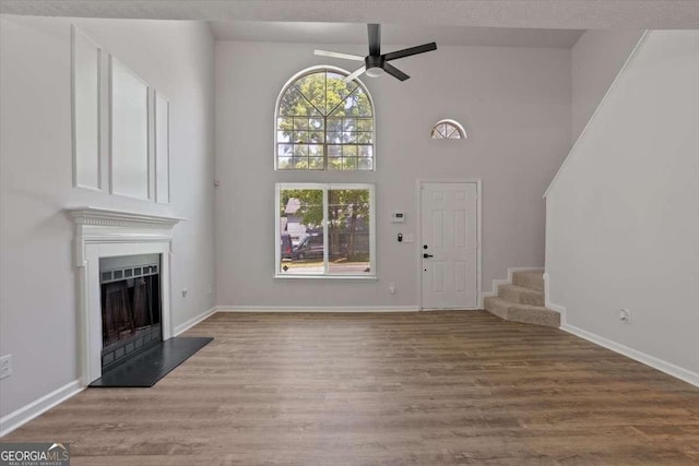 5383 Biffle Way, Stone Mountain, GA 30088 - unfurnished living room with stairway, a ceiling fan, a fireplace with raised hearth, wood finished floors, and high vaulted ceiling