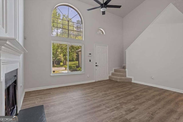 5383 Biffle Way, Stone Mountain, GA 30088 - unfurnished living room featuring a fireplace with flush hearth, ceiling fan, stairs, high vaulted ceiling, and plenty of natural light