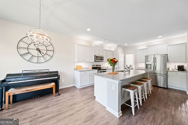 433 Crystal Way, Cornelia, GA 30531 - kitchen with stainless steel appliances, a kitchen breakfast bar, a chandelier, wood finished floors, and recessed lighting